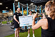 eos gym member side by side with personal trainer holding up white board indicating how much they lifted